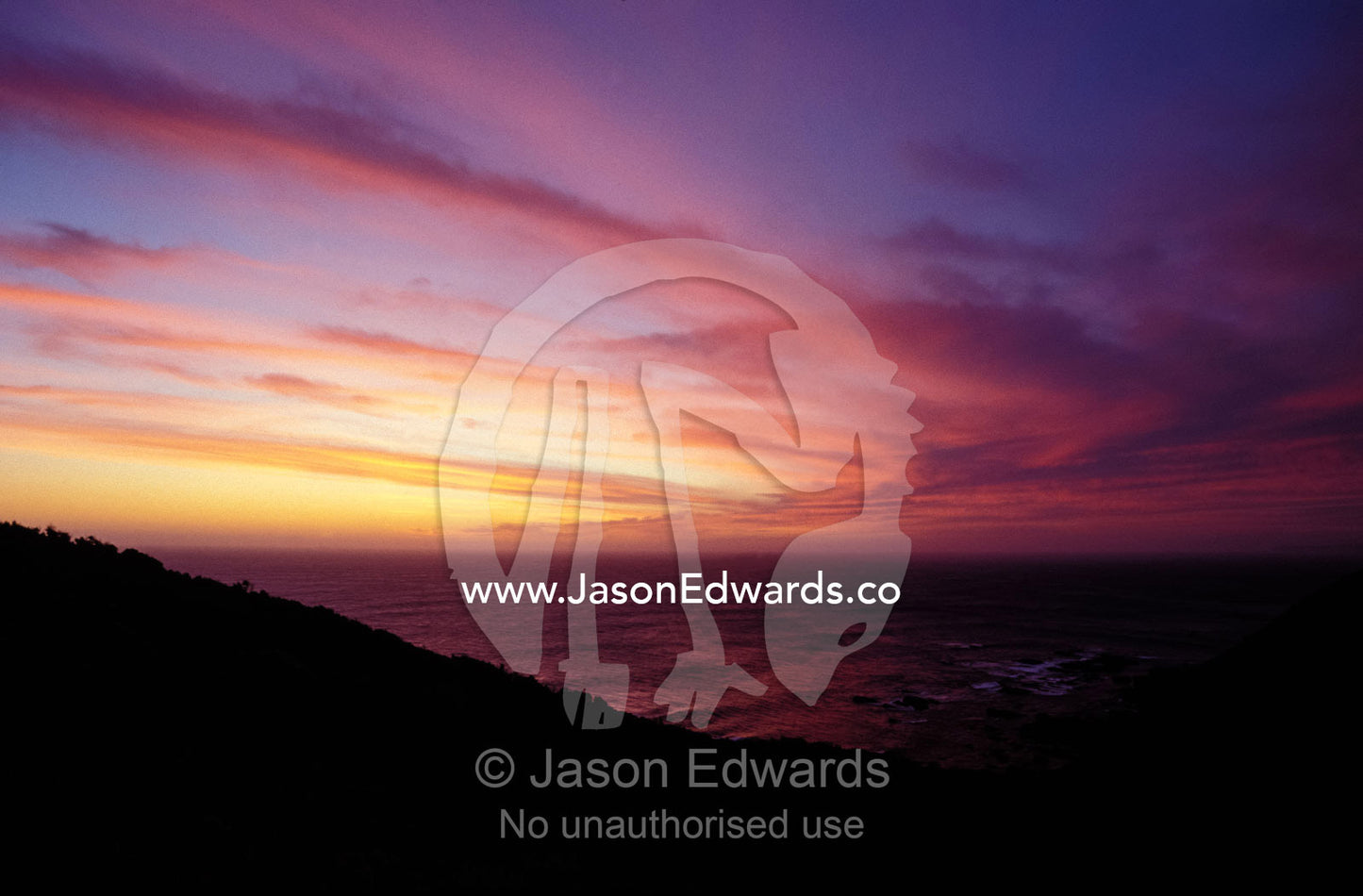 Sunset reflects off a cloud band passing over a rugged coastline. Cape Otway National Park Victoria Australia.