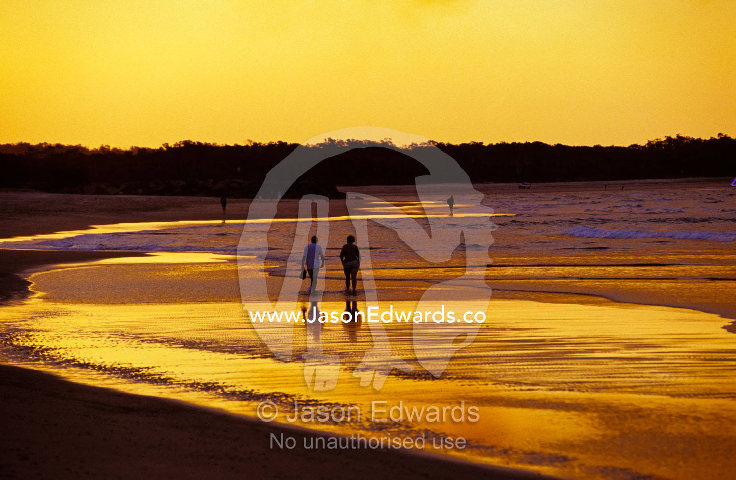 A couple going for a romantic walk on the beach at sunset. Noosa, Queensland, Australia.