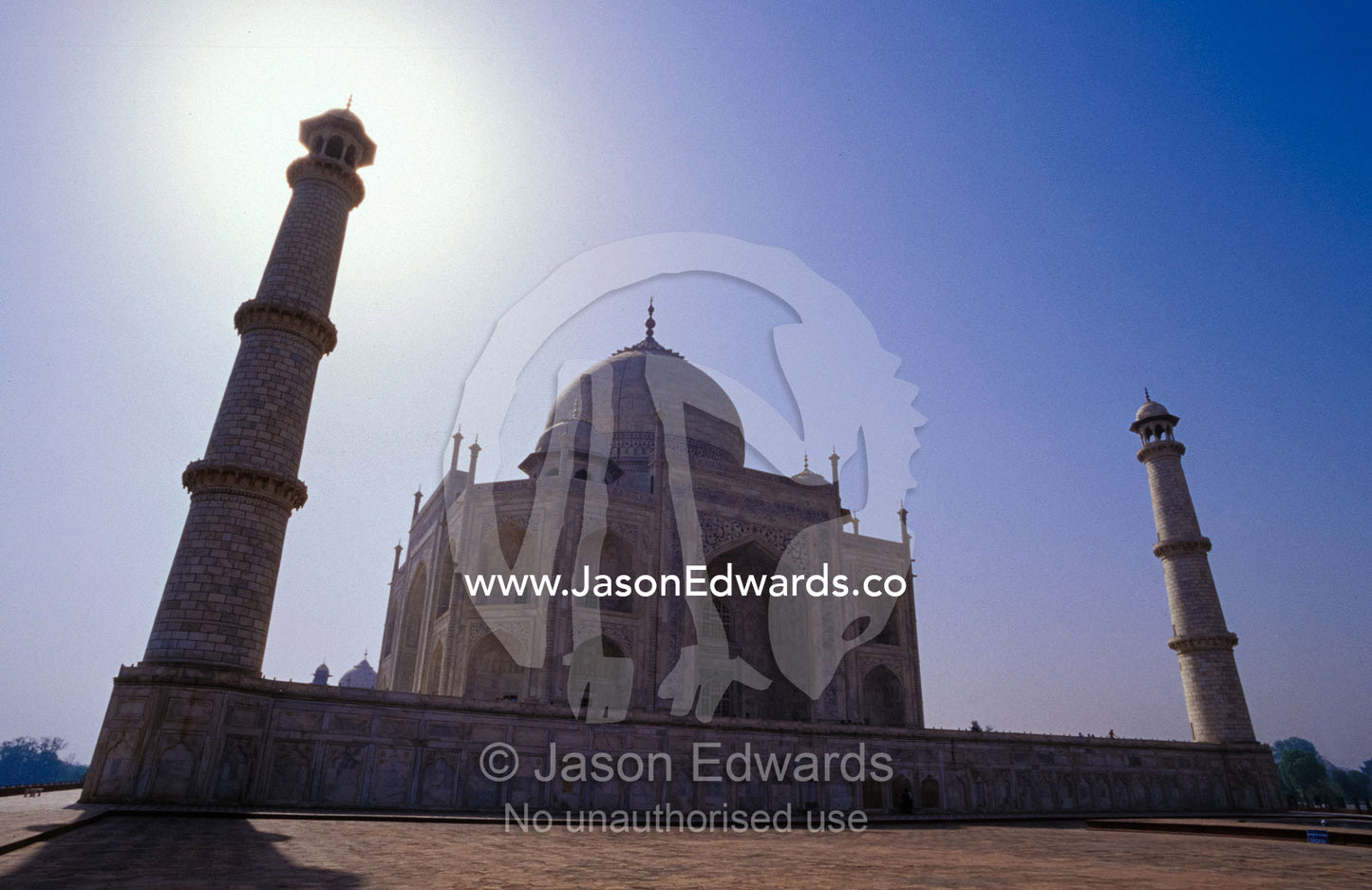 The Taj Mahal and two minarets silhouetted against a clear blue sky. Agra, India.