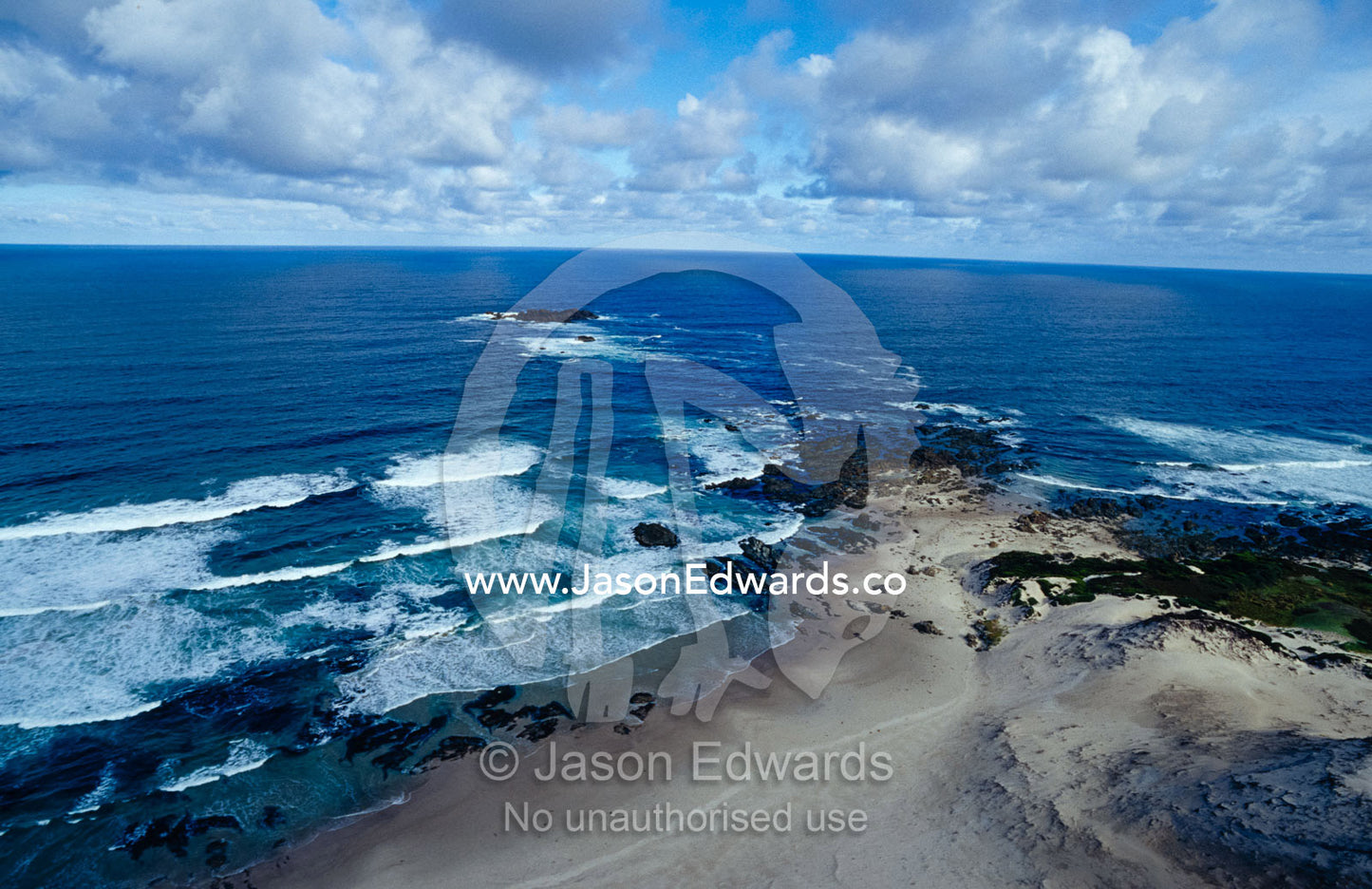 Waves smashing onto a rugged remote coastline beneath storm clouds. South West Conservation Area, Tasmania, Australia.