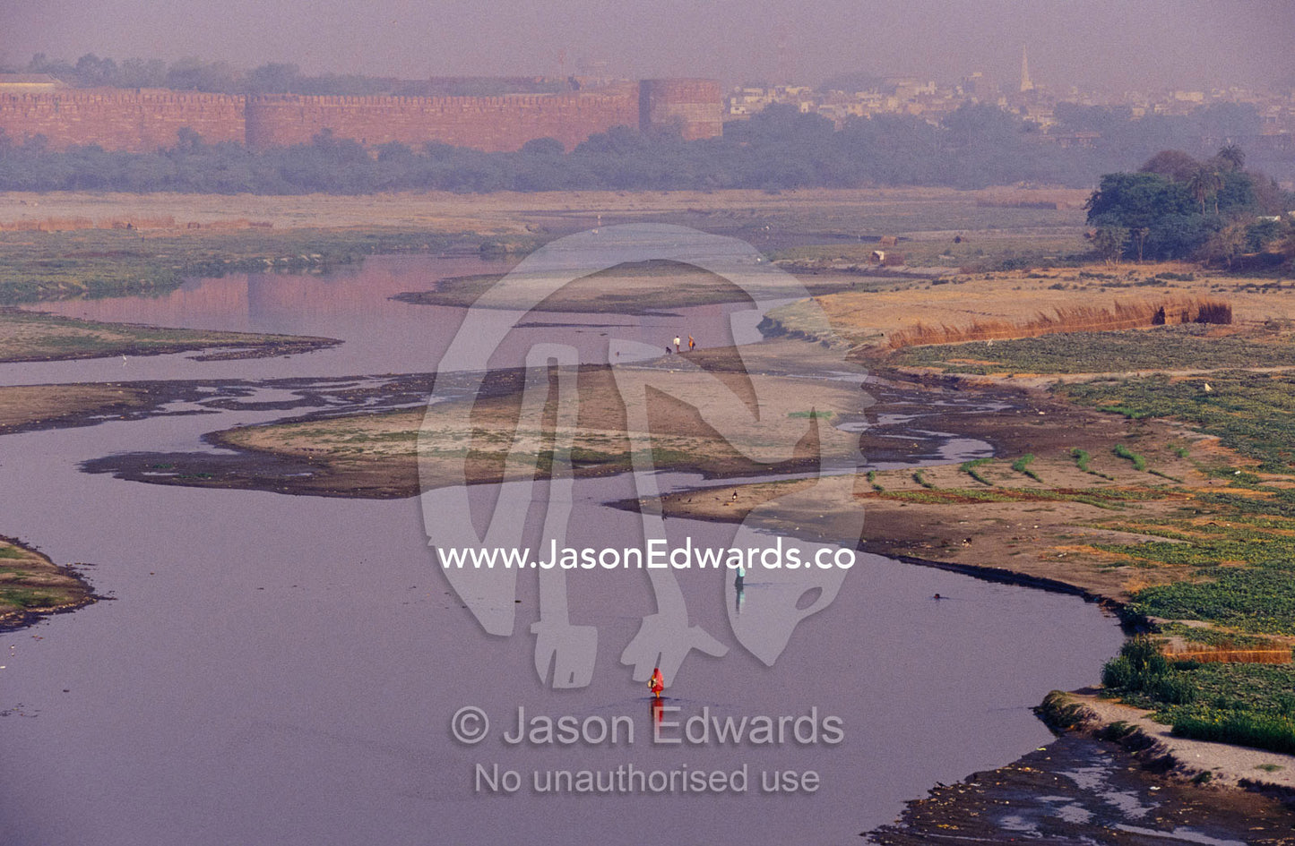 Women in saris wade across the Yamuna River floodplain at dawn. Agra, India.