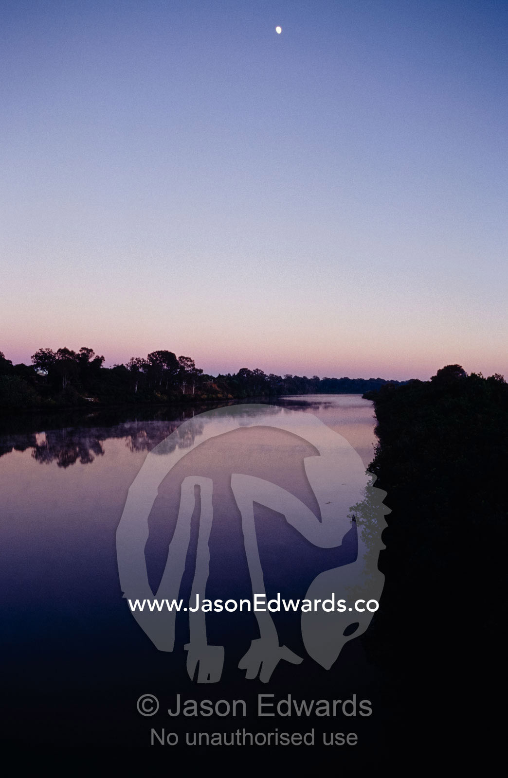 The moon high in a vast empty night sky pre-dawn over a calm river. Maryborough, Queensland, Australia.