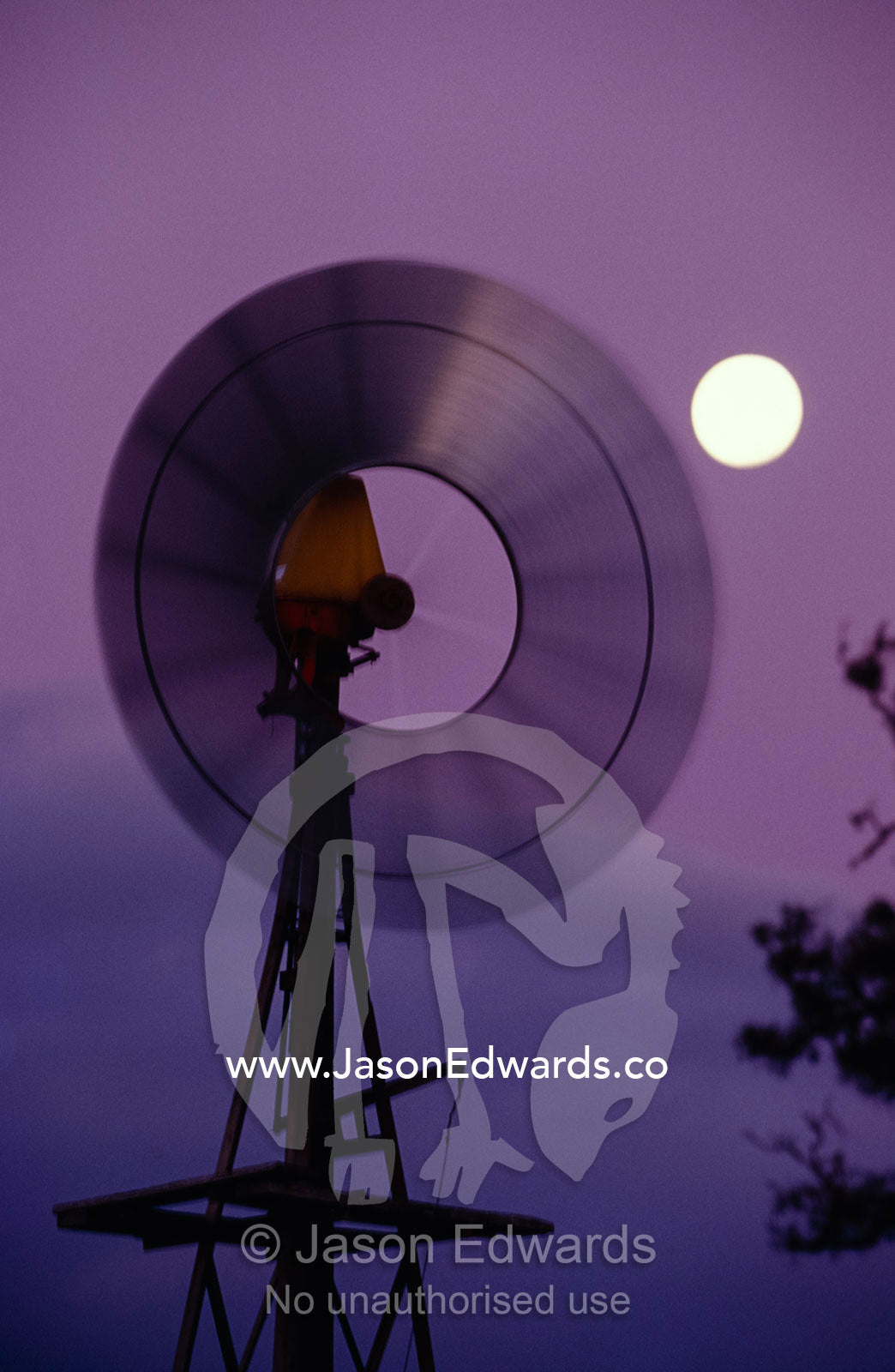 A rotating Windmill and a full moon in the purple sunset afterglow. Dunkeld, Victoria, Australia.