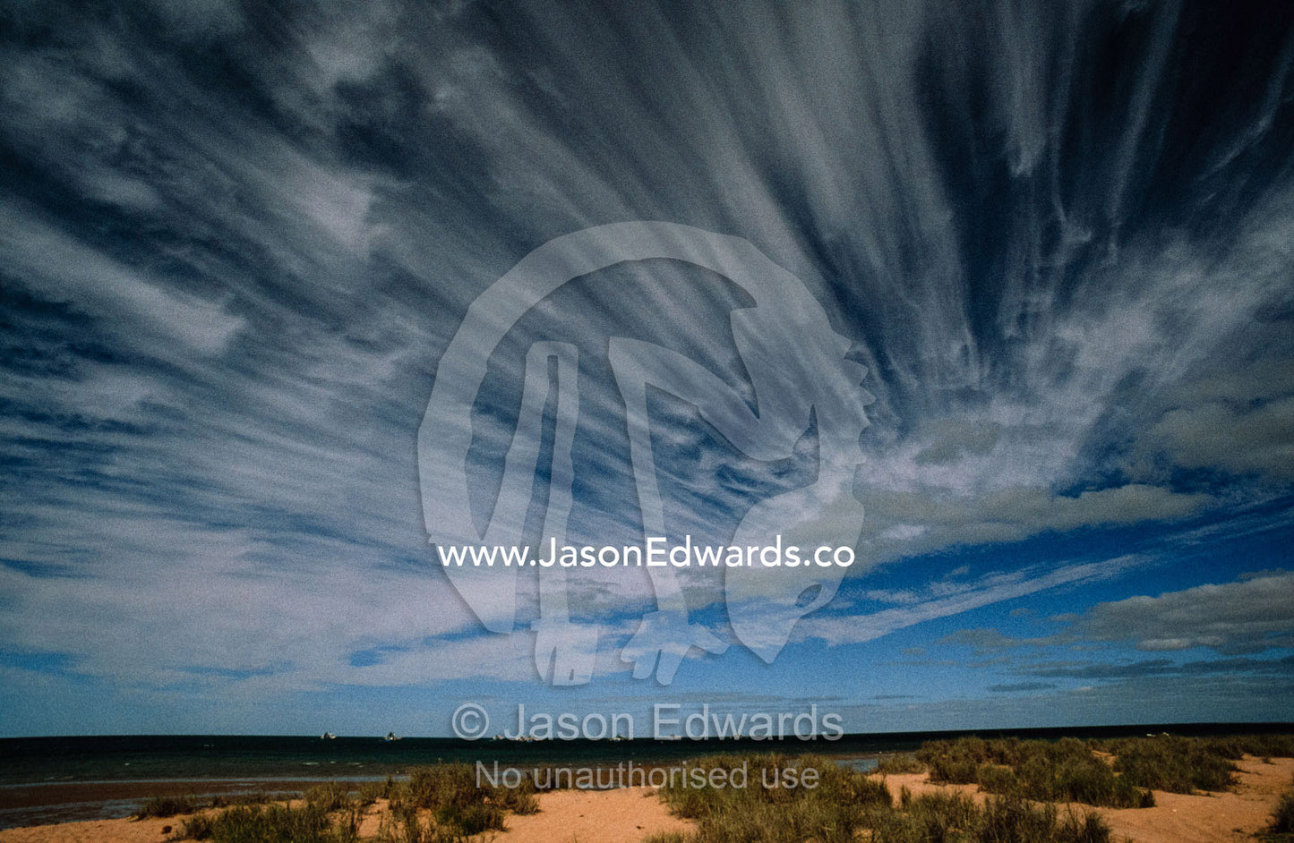Wind whipped clouds race toward the shore from the open ocean. Cape Range National Park, Western Australia.