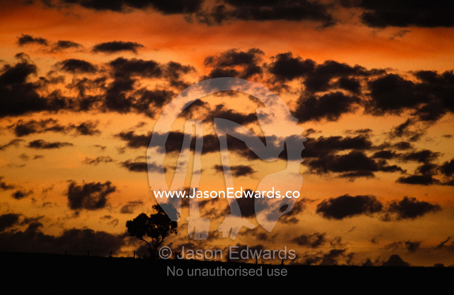 Fall storm clouds over a mountain ridge and farm fence at sunset. Eyre Peninsula, South Australia.