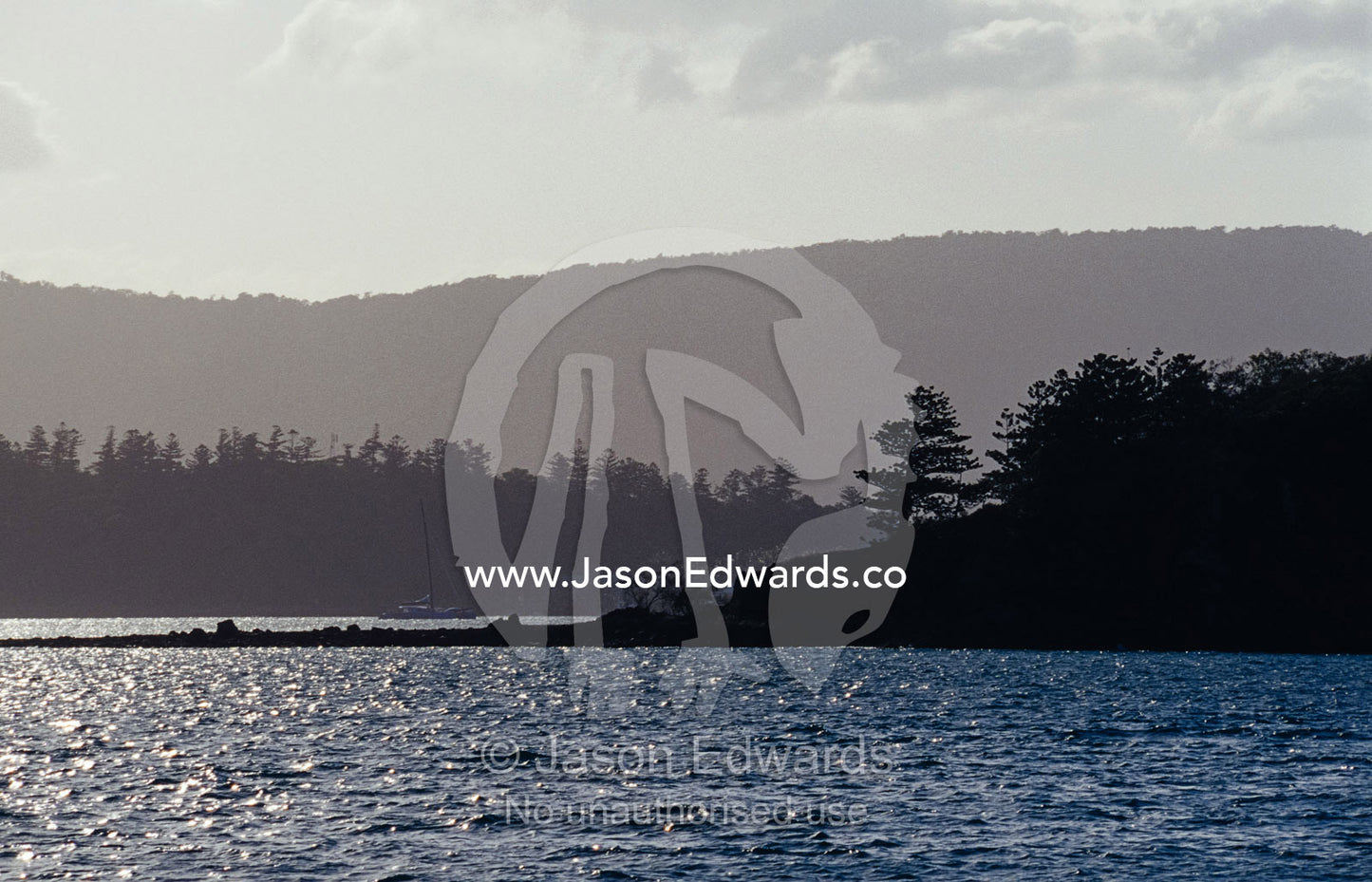 Small tropical islands covered in pine forest silhouetted at sunset. Whitsunday Islands, Queensland, Australia.