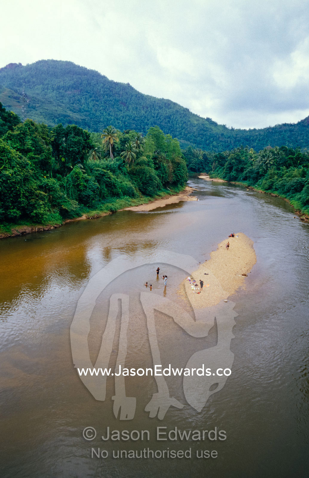 Villagers bathe and do laundry in a rainforest lined river. Central, southern, Sri Lanka.
