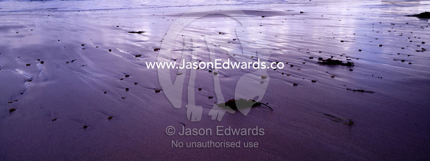 Storm clouds reflected in wet sand on a stony beach at low tide. Jan Juc, Victoria, Australia.