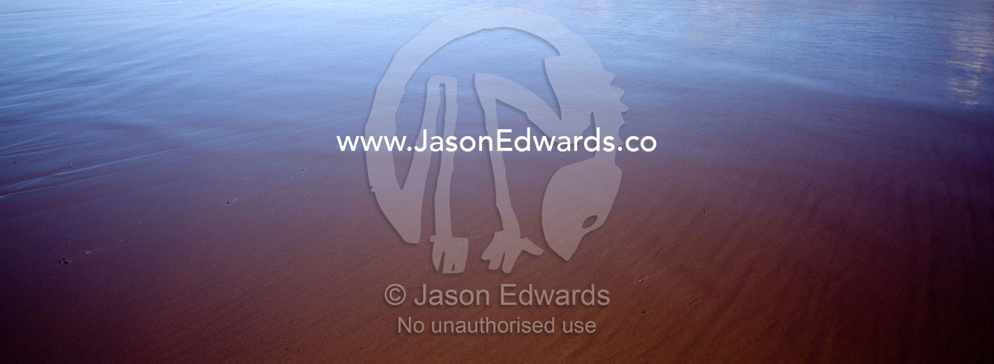 A clear blue sky reflected in a smooth wet beach at low tide. Jan Juc, Victoria, Australia.