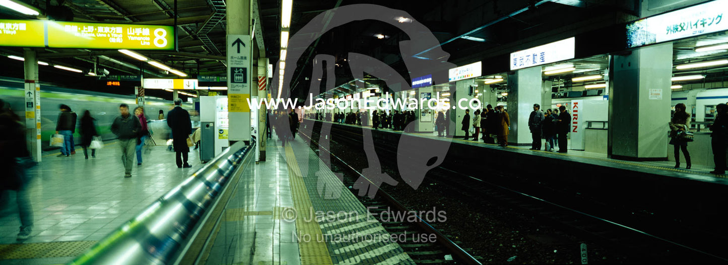 Commuters wait on railway platforms to catch trains in the subway. Ikebukuro Station, Tokyo, Japan.