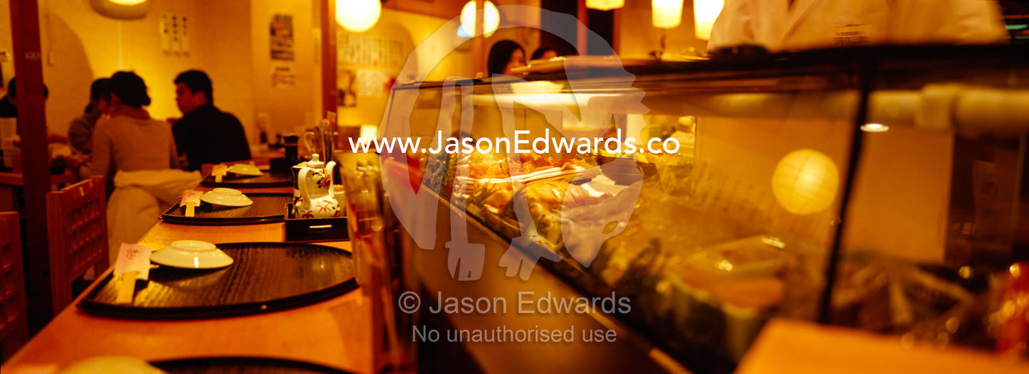 Diners and a display of fresh fish and other delicacies in a Sushi bar Tsukiji Fish Market, Tokyo, Japan.