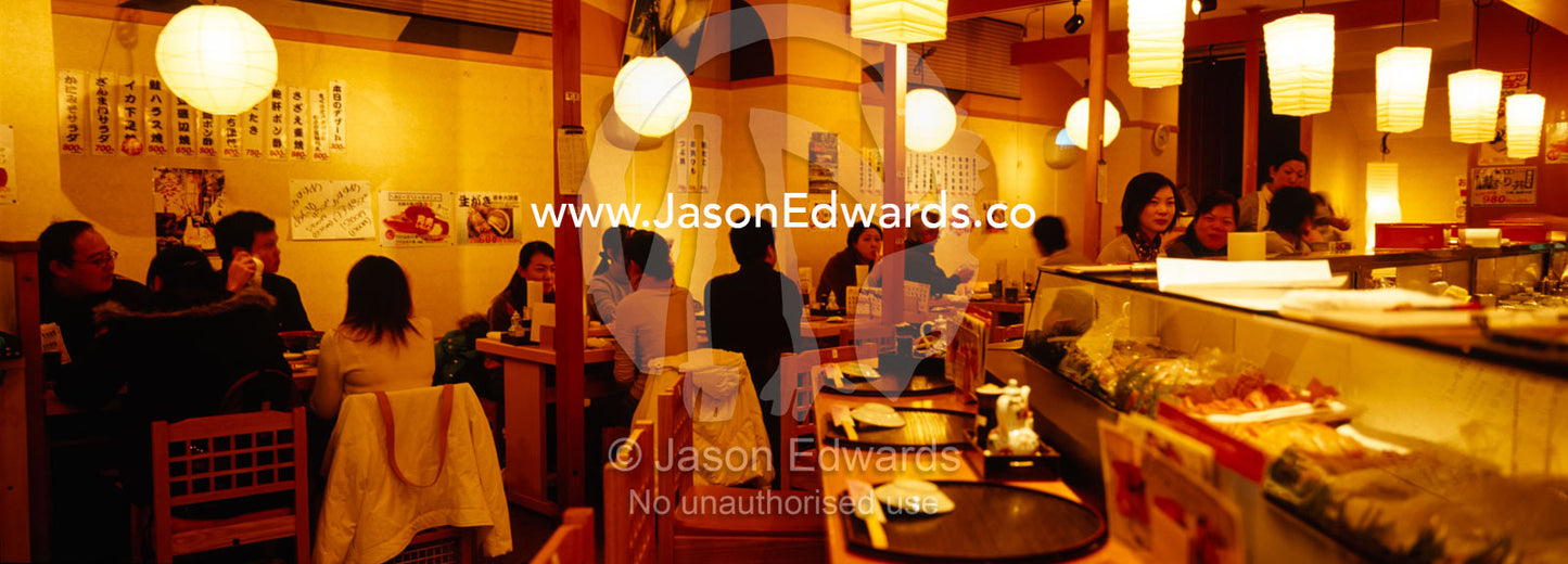 Diners and a display of fresh fish and other delicacies in a Sushi bar Tsukiji Fish Market, Tokyo, Japan.