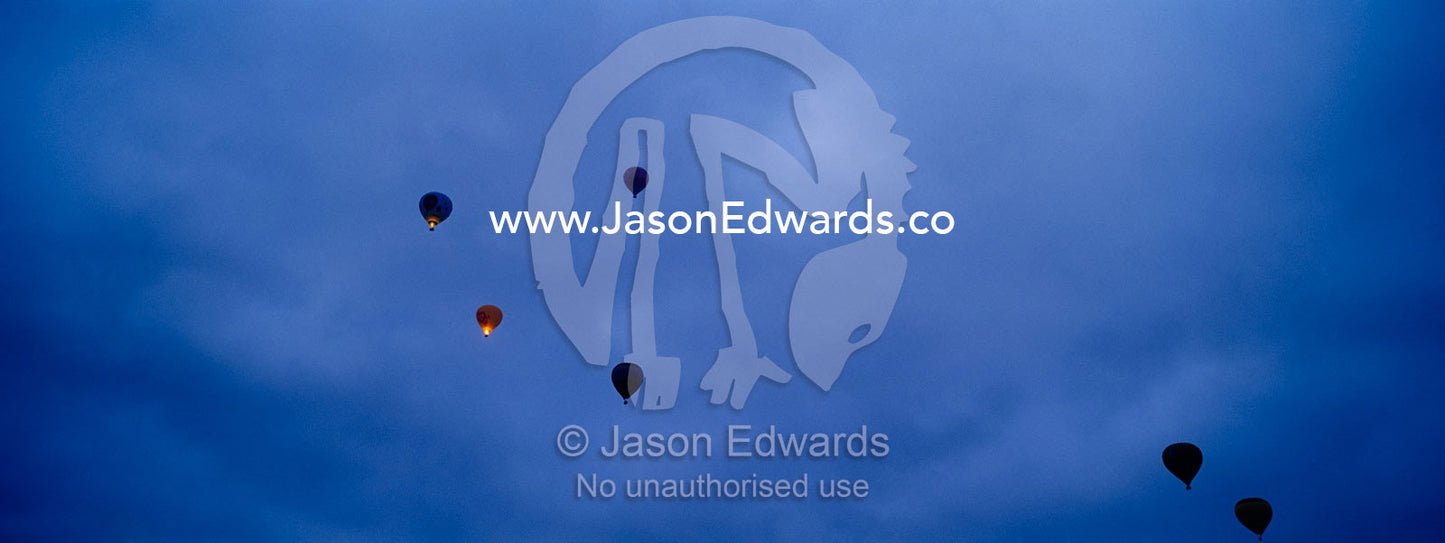 Hot air balloons rise into a menacing and stormy sky before dawn. North Carlton, Victoria, Australia.