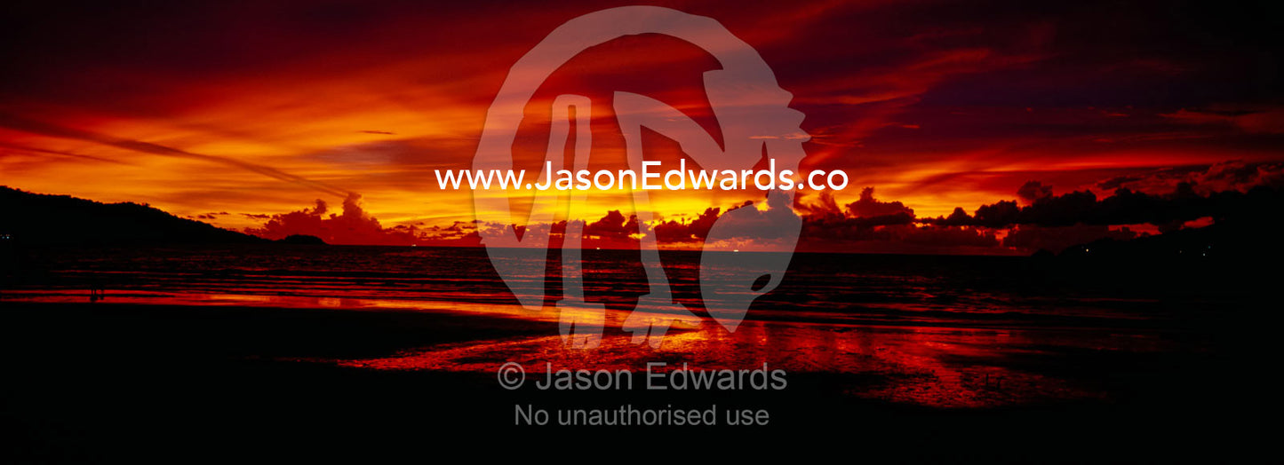 A flaming sunset erupts over Patong's famous beach and promenade. Patong Beach, Phuket, Thailand.