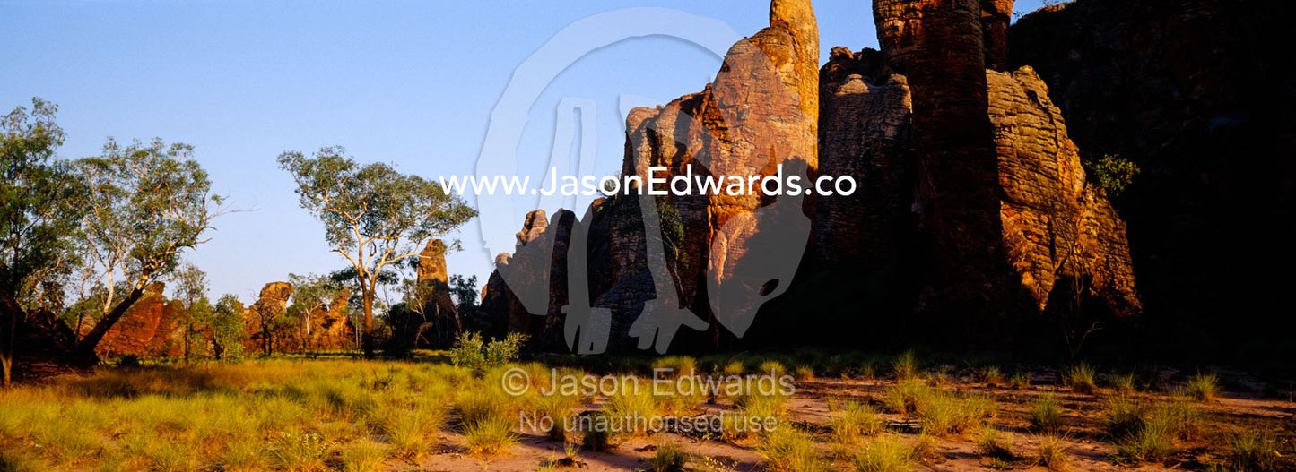 Ancient red rock formations rise above spinifex grasslands at sunset. Limmen National Park, Northern Territory, Australia.