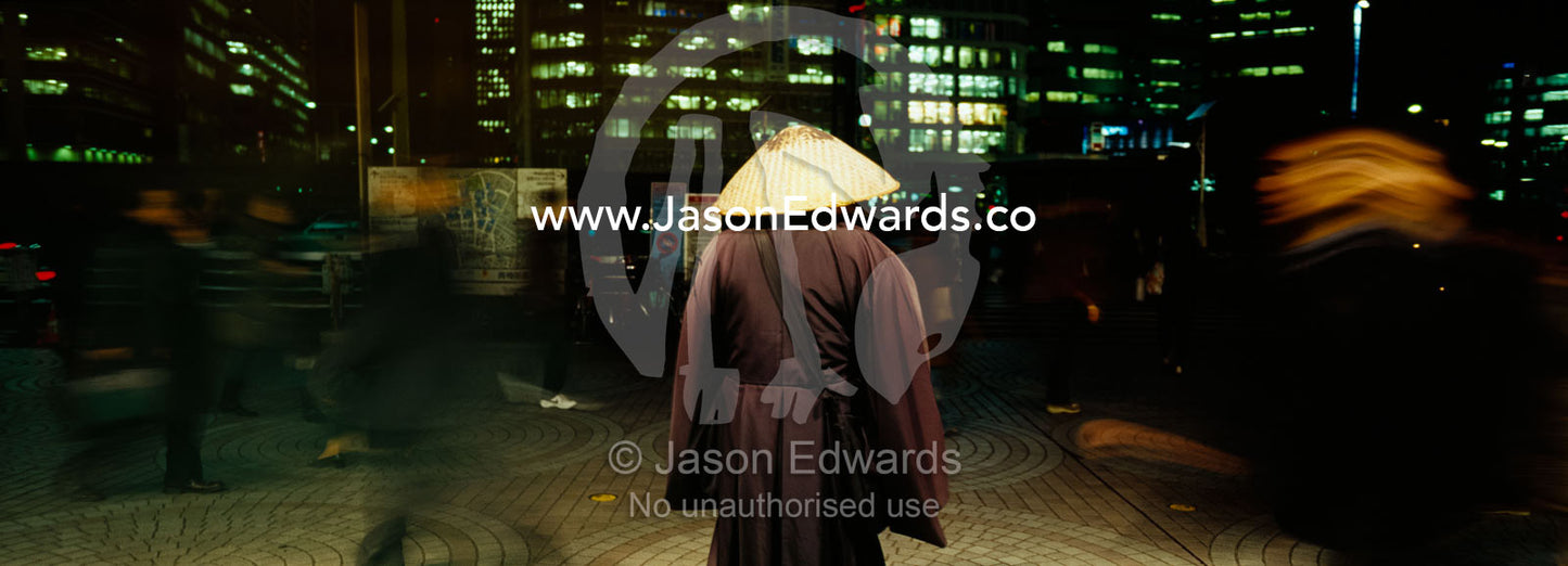 A Buddhist monk offers prayers to rail commuters at Shinjuku Station. Shinjuku Railway Station, Tokyo, Japan.