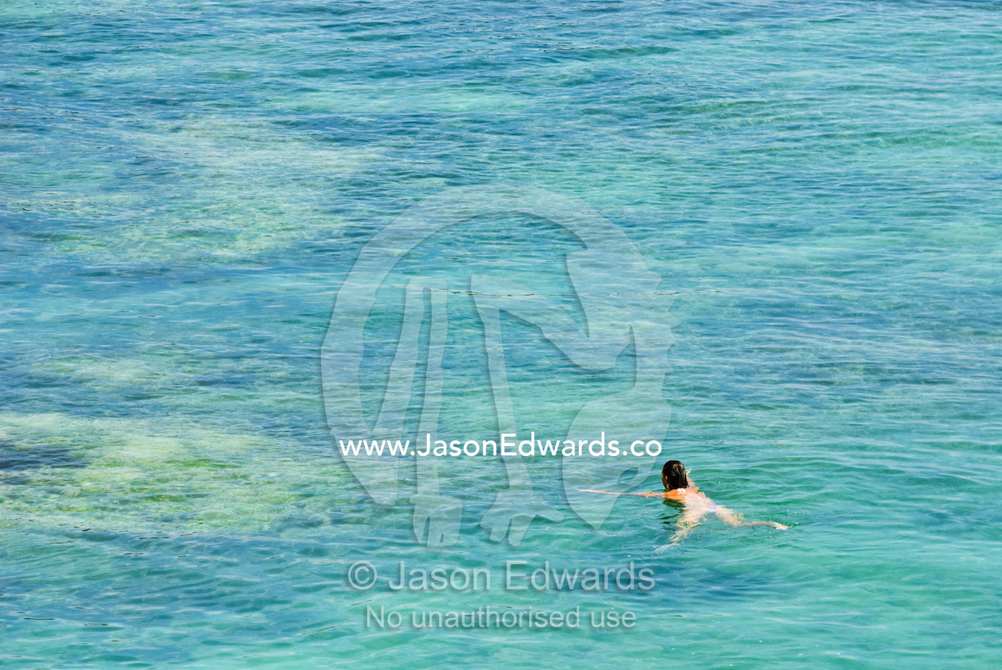 A lady enjoys swimming over the reef at Uluwatu's famed surfing break. Uluwatu, Bukit Peninsula, Bali, Indonesia.