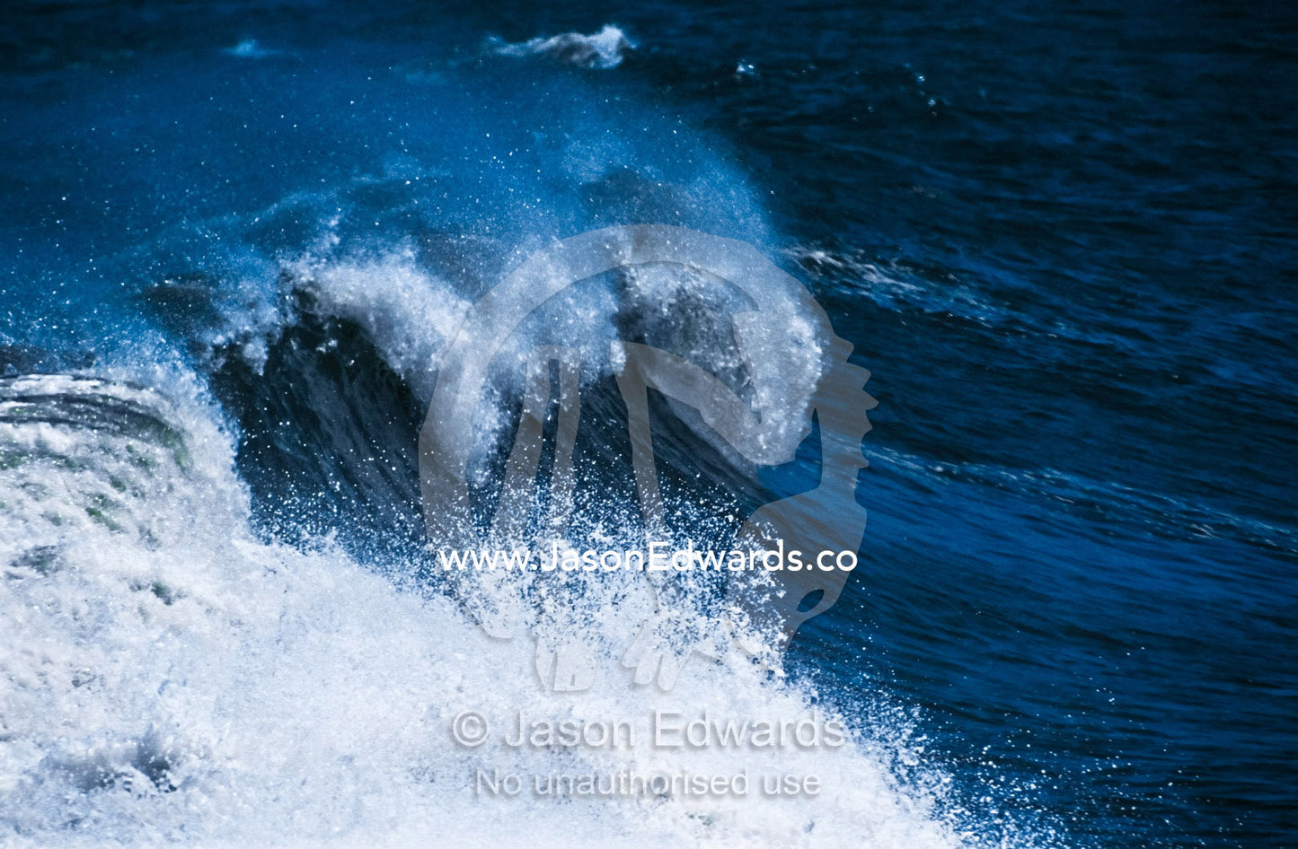 The curling lip of a huge wave breaks on a rugged desert coastline. Cape Cross, Skeleton Coast, Namibia.