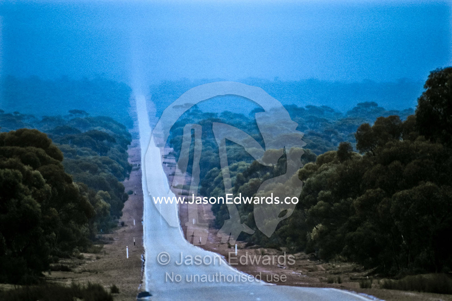 A rain storm falls over a long, straight road on the Nullarbor Plain. Nullarbor Plain, Western Australia, Australia.