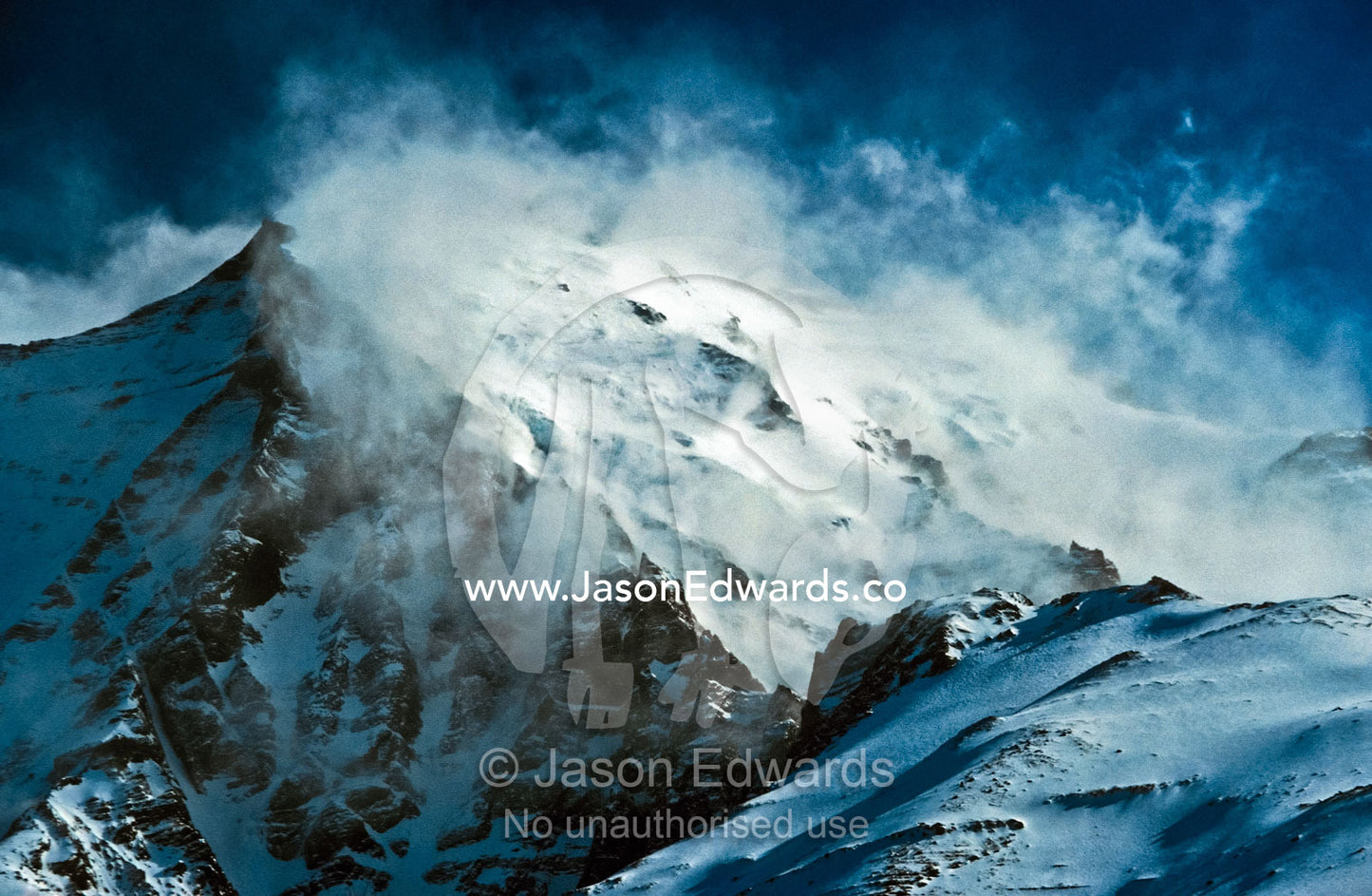 Light clouds sweep a mountain face in the Andes Range during Spring. Torres del Paine National Park, Parque Nacional Torres del Paine, Chile.