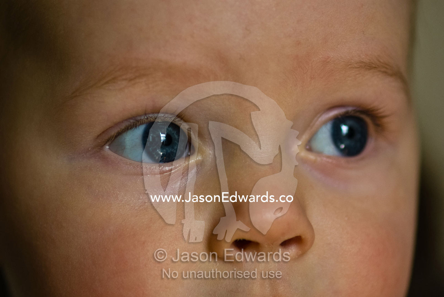 The clear, bright blue eye and button nose of an innocent baby boy. Collingwood, Victoria, Australia.