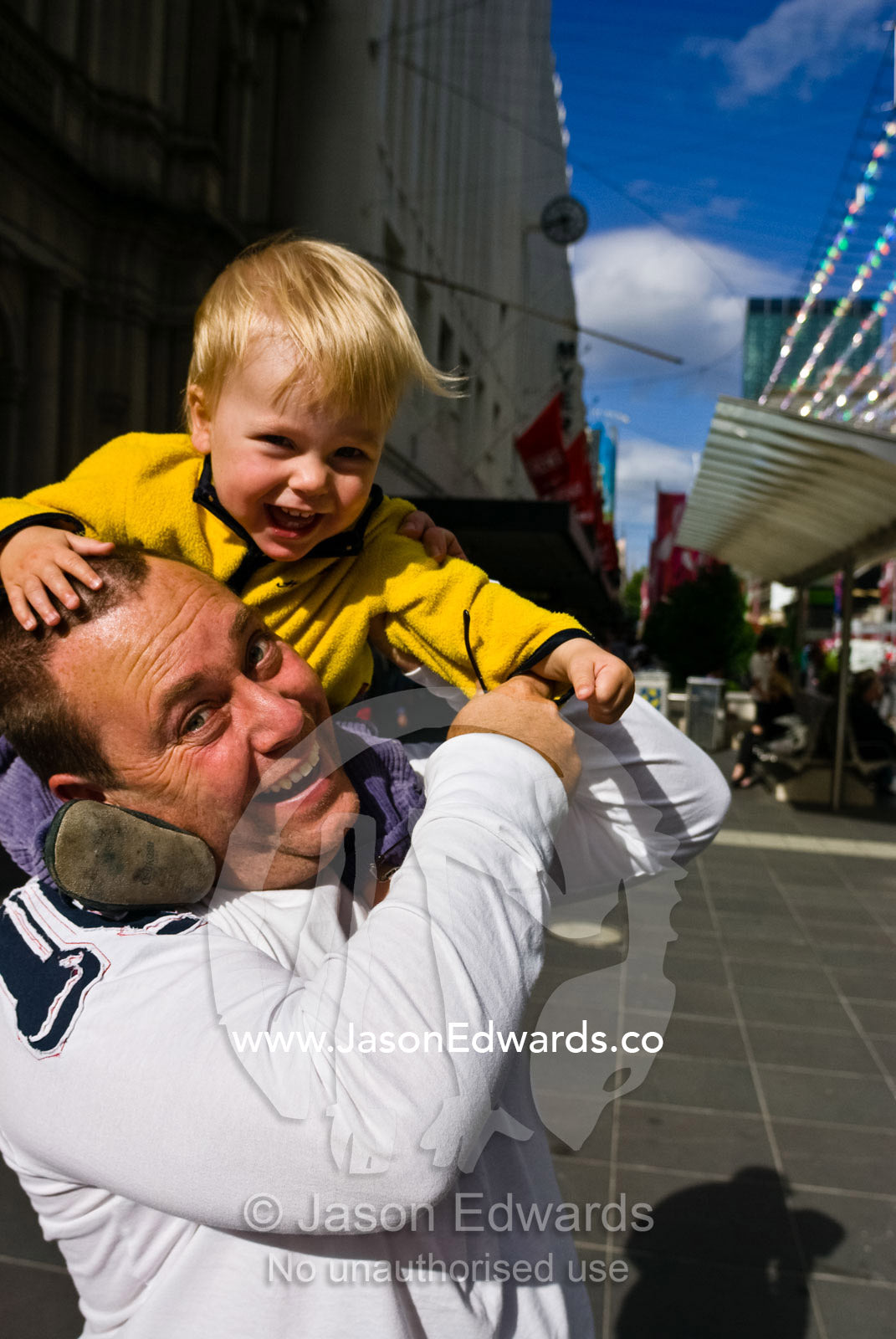 A father and son play piggyback games in a city mall on Christmas eve. Melbourne, Victoria, Australia.