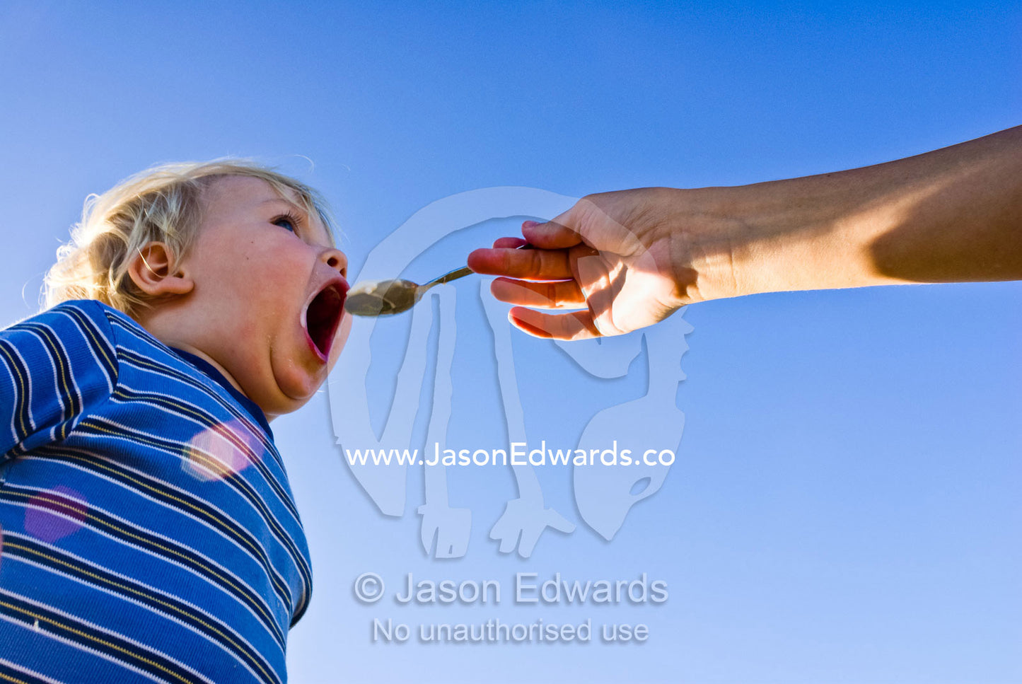 A baby gulps down fresh, cold yogurt on a hot summer afternoon. Torquay, Surf Coast, Victoria, Australia.