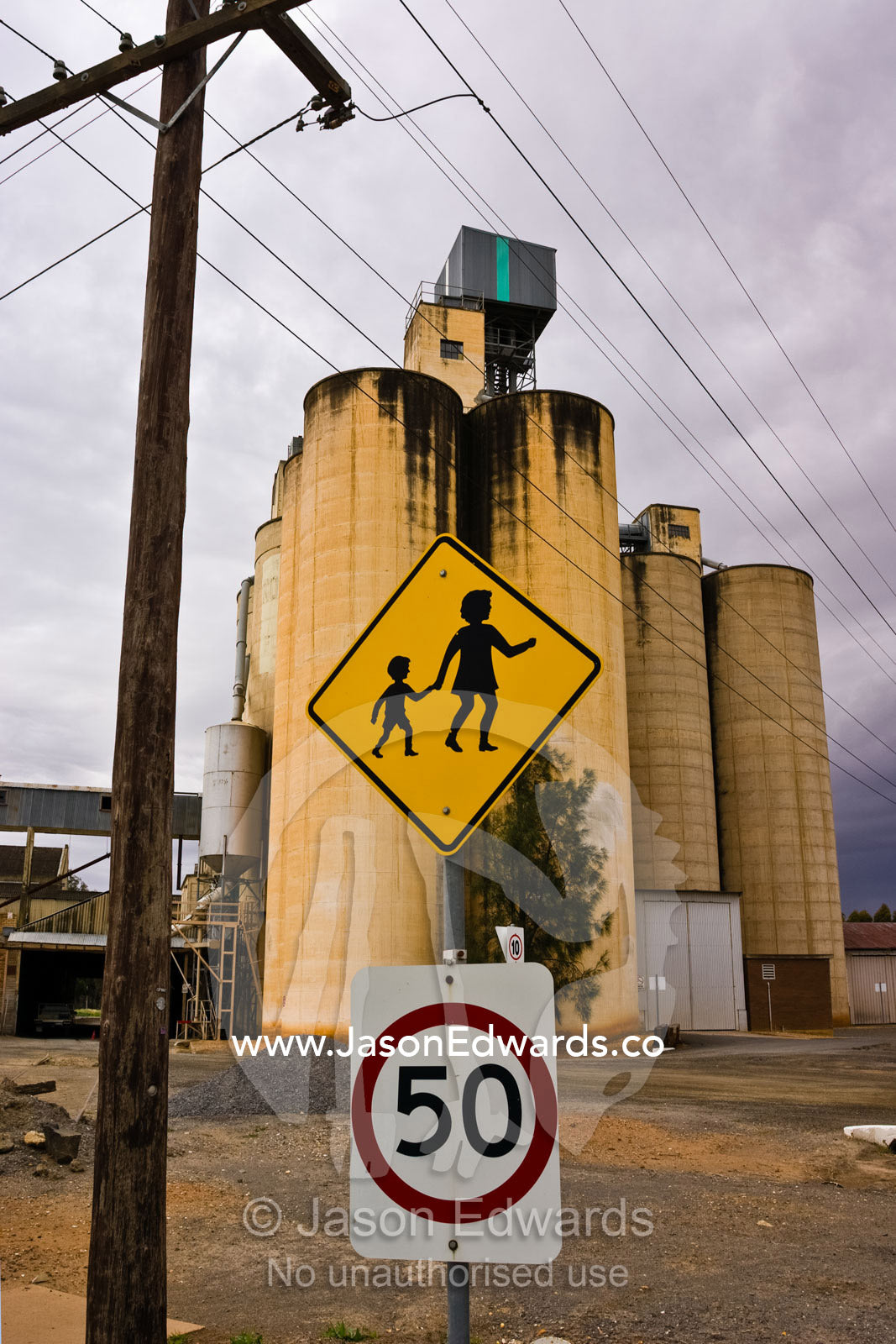 A speed warning marks a childrens' school crossing next to a silo. Charlton, Victoria, Australia.
