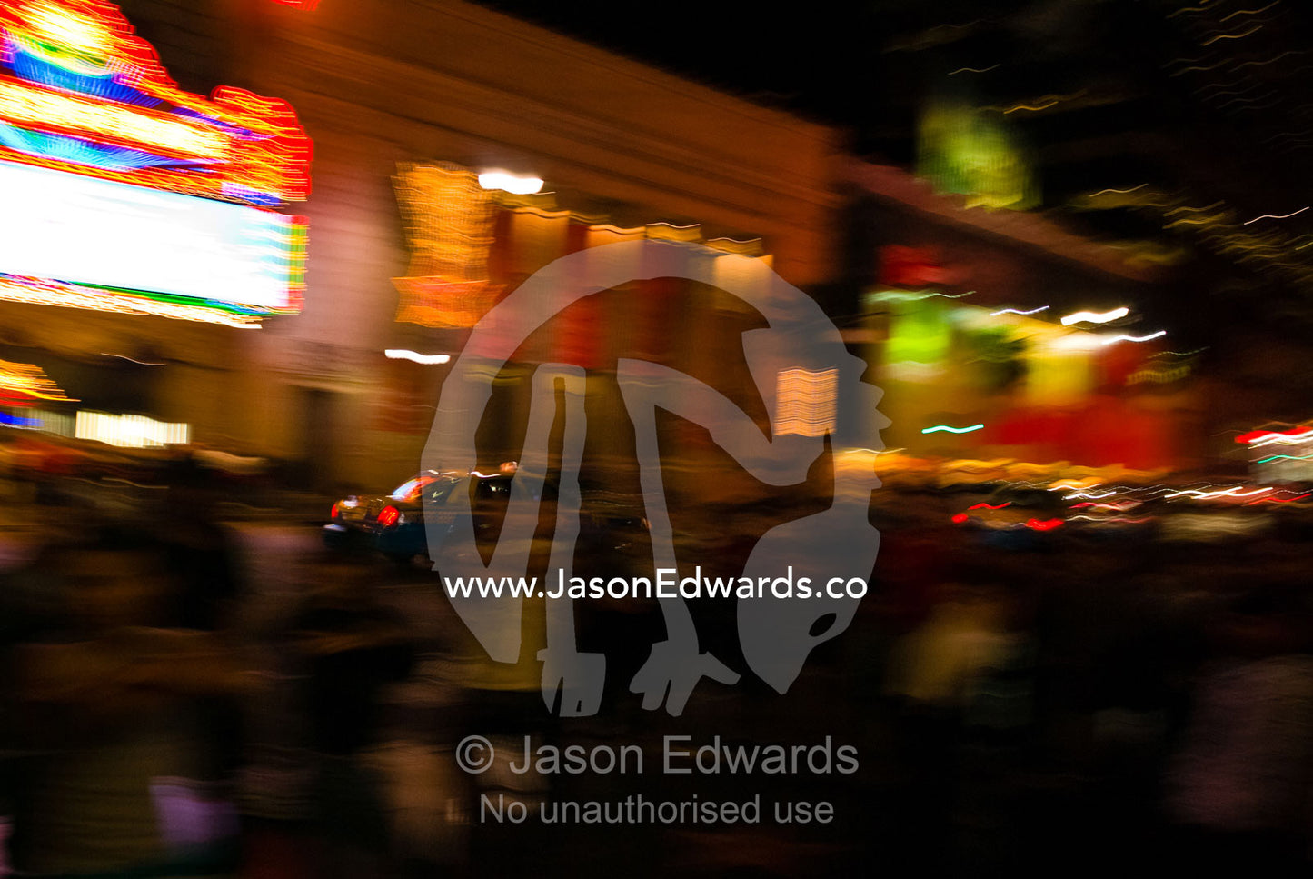 A cab speeds past tourists and the flaming neon lights of Hollywood. Hollywood Boulevard, Los Angeles, California.