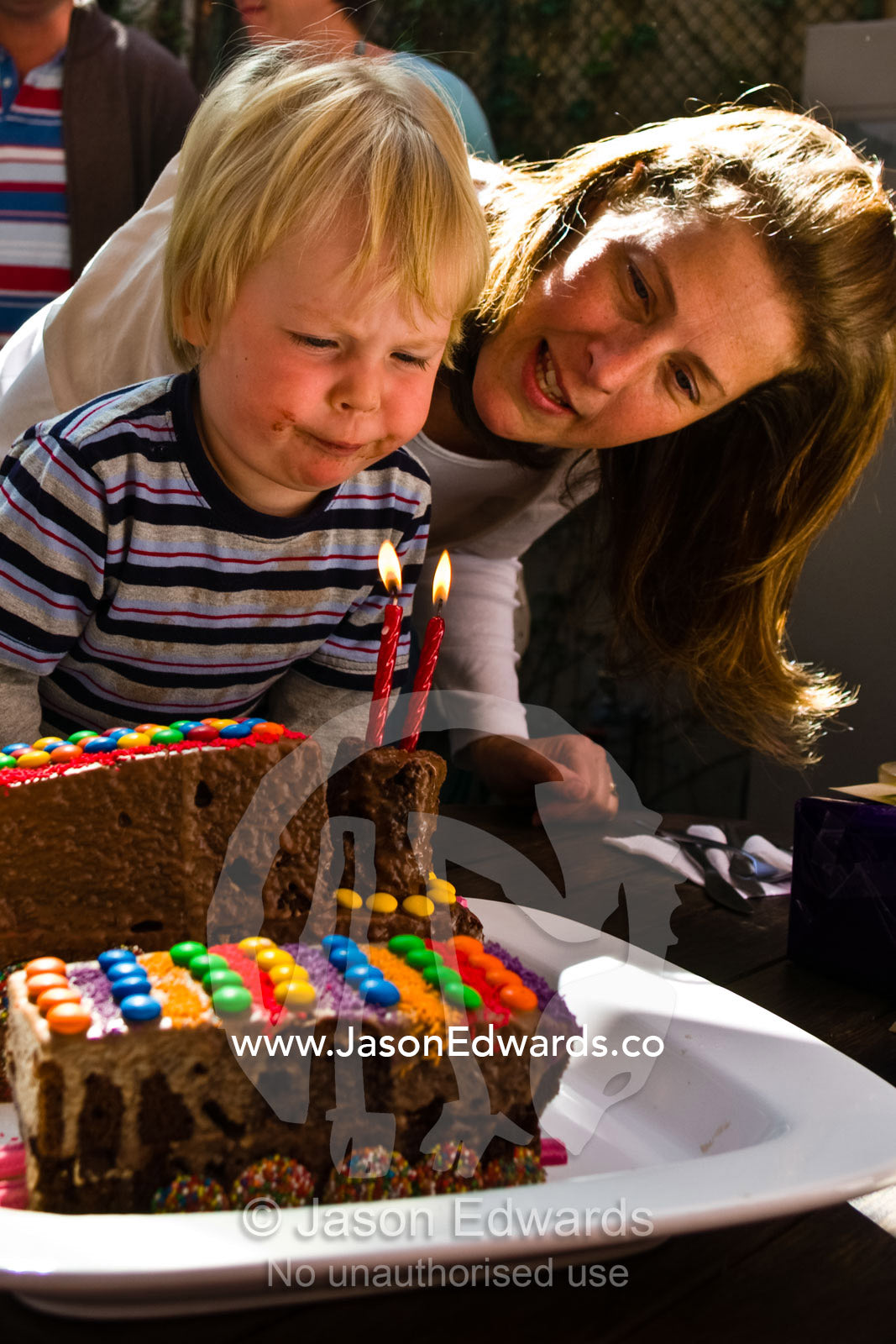 A two year old concentrates hard at blowing out his birthday candles. Fitzroy, Victoria, Australia.