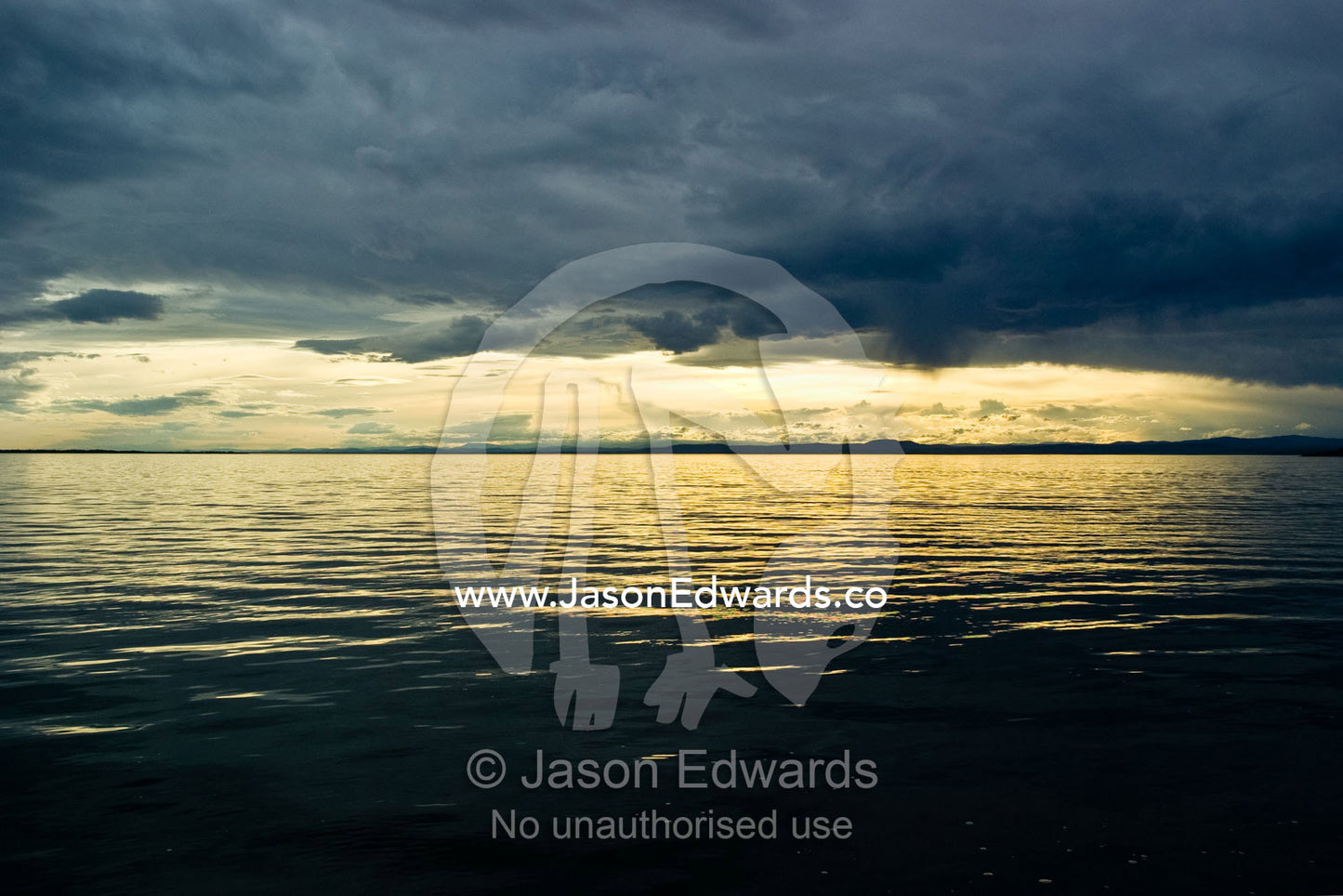 A winter storm descends over a calm coastal lake at sunset. Lake King, Gippsland Lakes, Victoria, Australia.