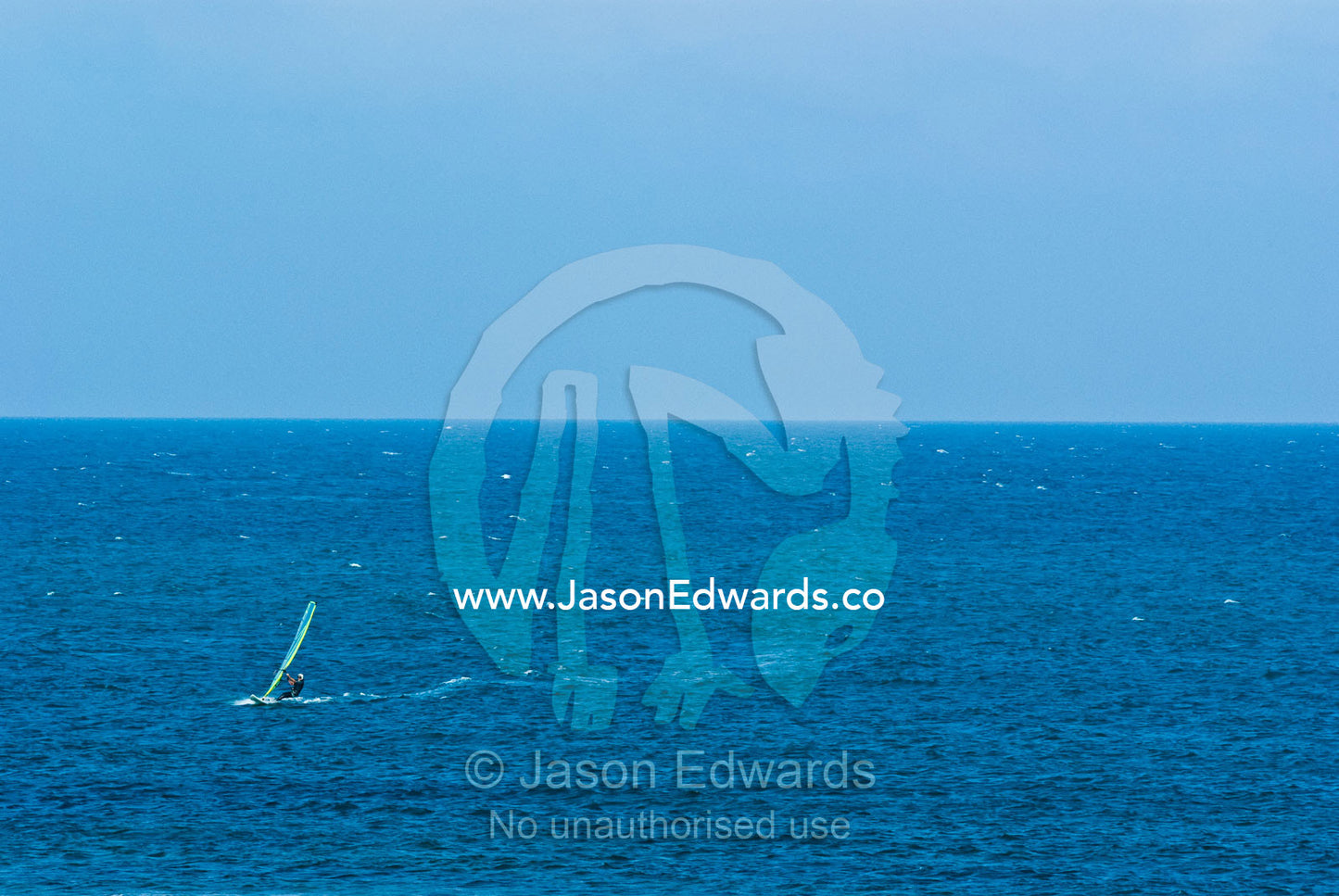 Windsurfers harness the onshore winds to race across a turquoise sea. Point Danger, Cosy Corner, Torquay, Victoria, Australia.
