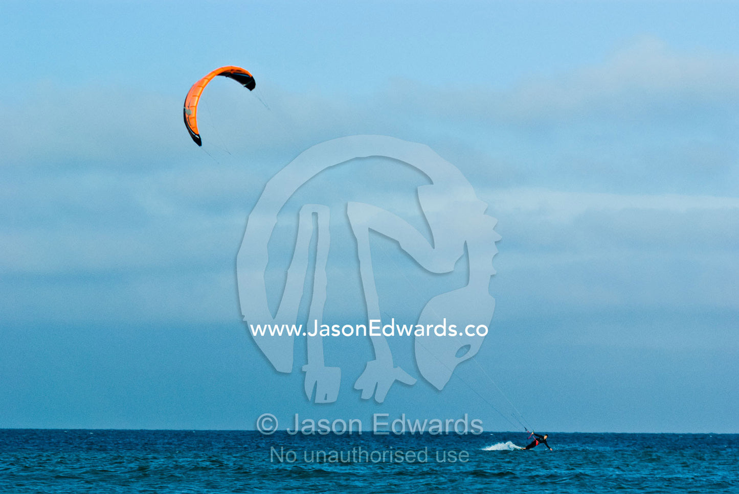 A kitesurfer races across a turquoise sea. Point Danger, Cosy Corner, Torquay, Victoria, Australia.