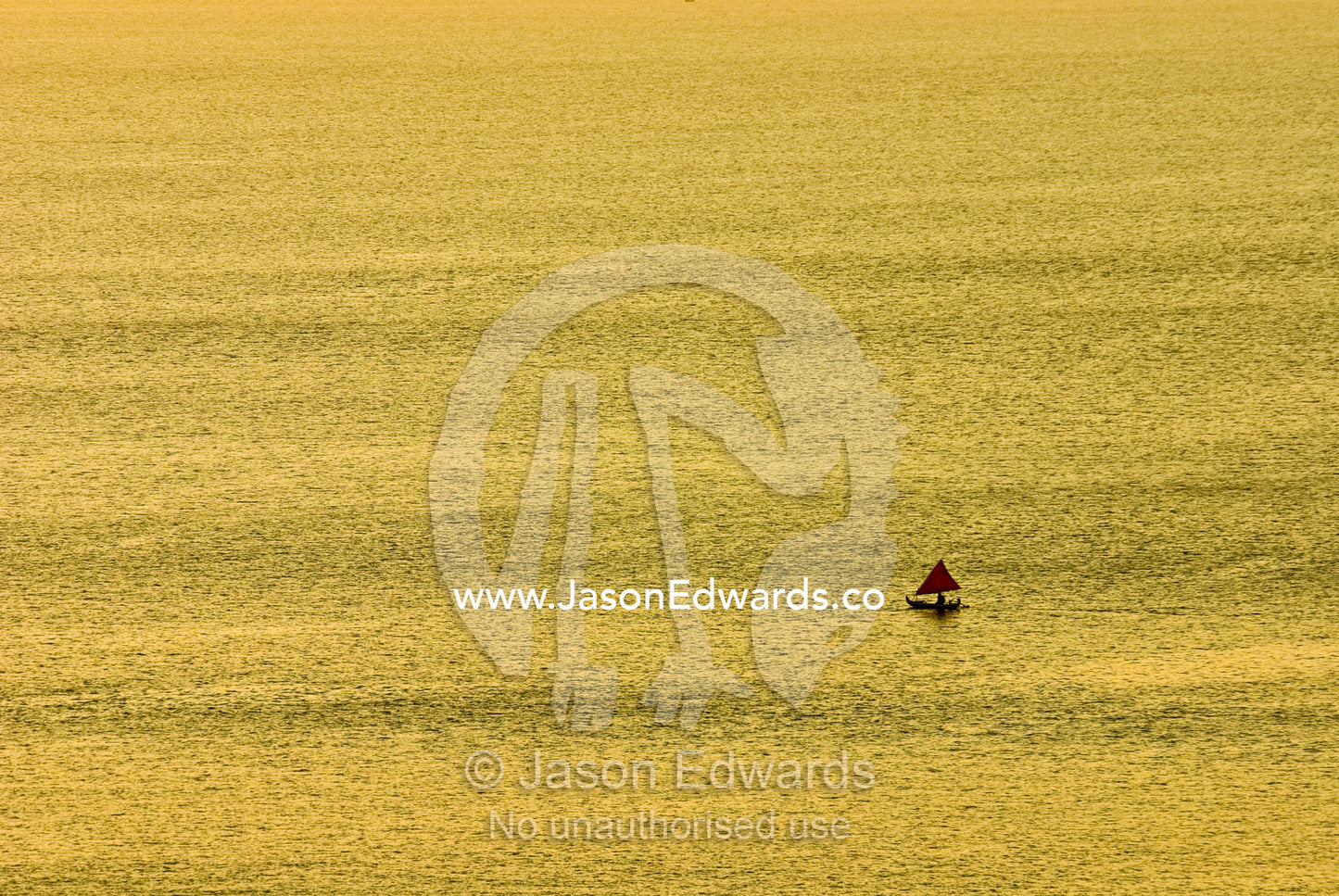 A small fishing boat heads out to sea at sunset for its nightly catch. Indian Ocean, Bukit Peninsula, Bali, Indonesia.