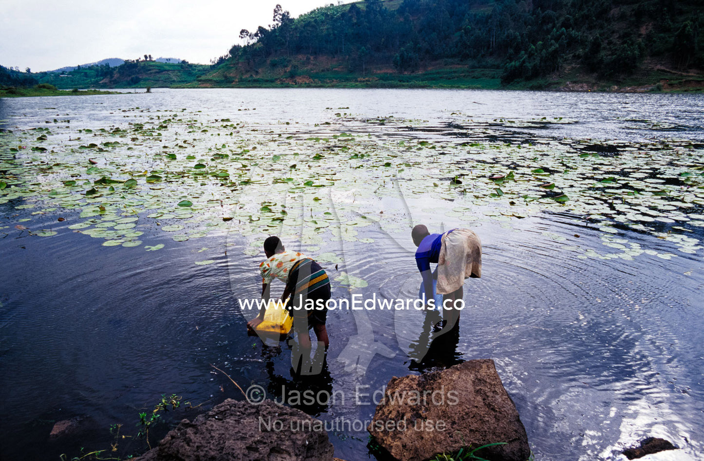 Teenage village girls collect fresh water from a volcano caldera lake. Lake Chahafi, Kisoro District, South Western Uganda.