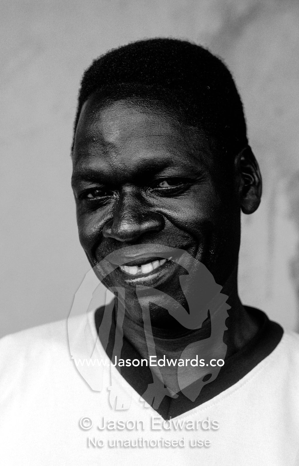 A smiling young East African man resting in a roadside truck stop. Tororo District, Eastern Uganda.