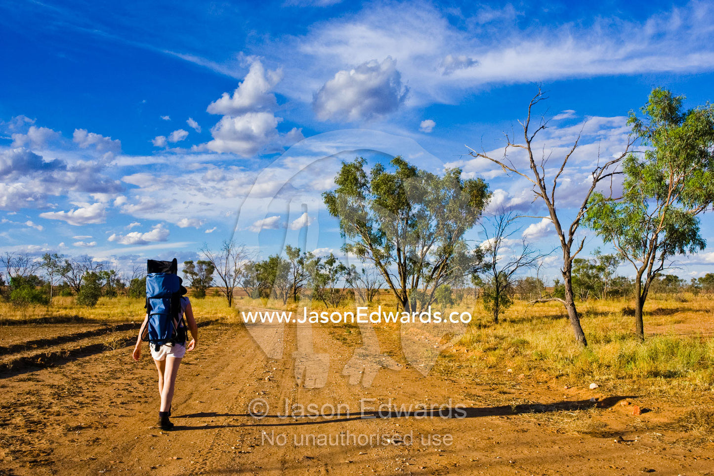 A mother carries her baby on her back whilst hiking in the outback. Sturt National Park, New South Wales, Australia.