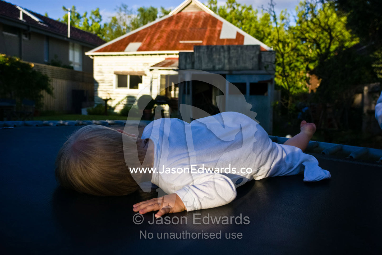 An exhausted baby rests on a trampoline after a long Christmas Day. Malvern East, Victoria, Australia.
