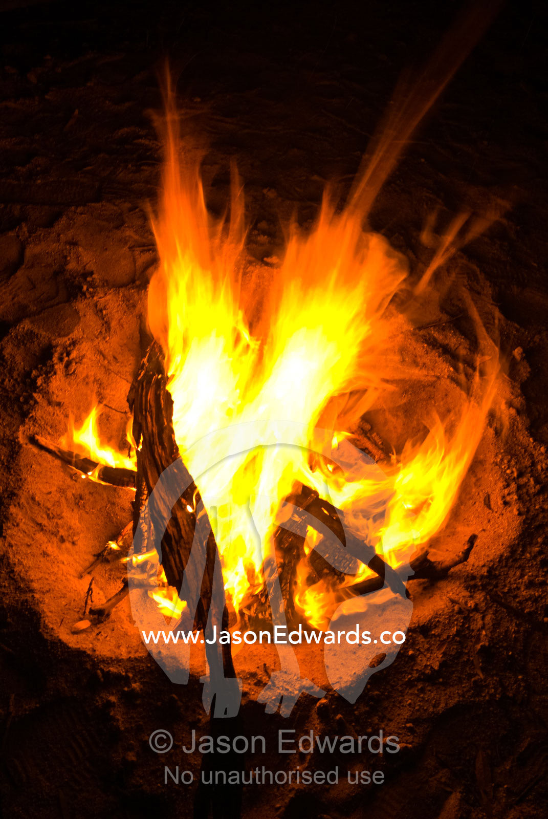 A camp fire blazes in the safety of the sand of a dry riverbed. Bullatail Creek, Mundiwa Station, Deniliquin, New South Wales, Australia.