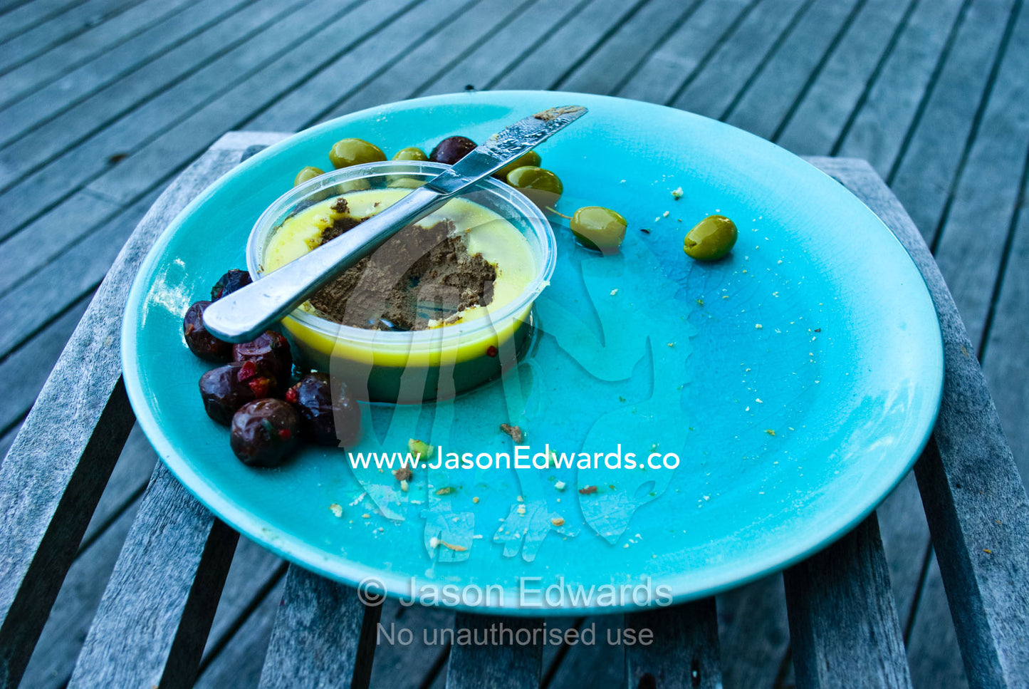 The remains of a feast of olives and pate dip on a balcony decking. Flinders, Mornington Peninsula, Victoria, Australia.