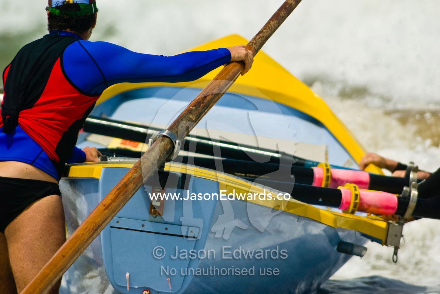 An oarsman known as a sweep waits to steer a surf boat in rough seas. Australian Surfboat Open Titles, Fishermen's Bay, Torquay, Victoria, Australia.