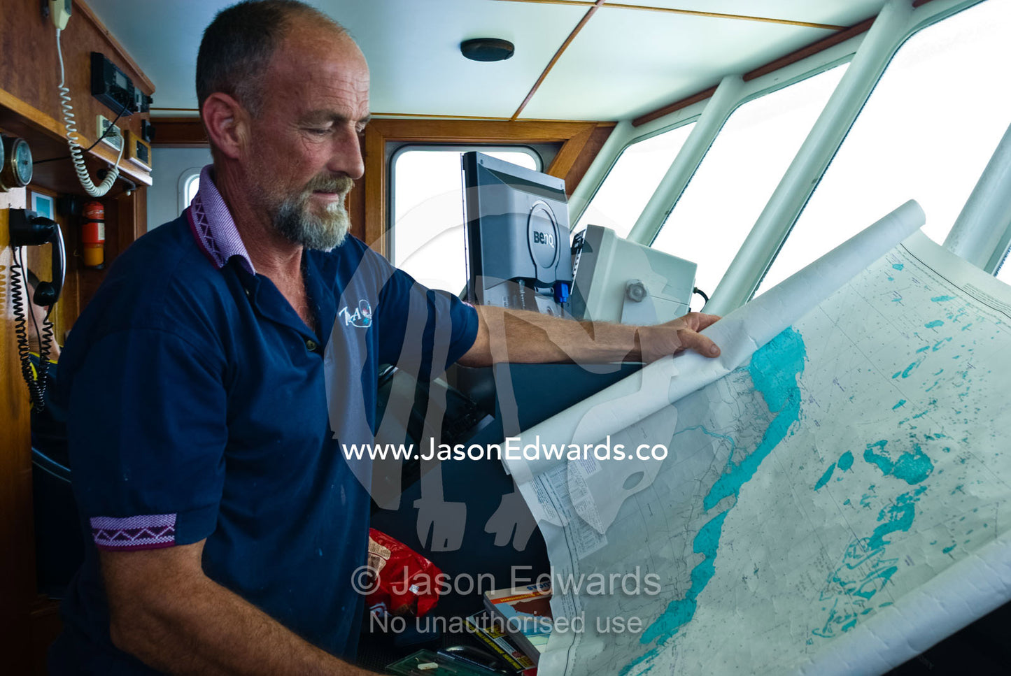 A ships captain examines a maritime map highlighting dangerous reefs. Coral Sea, Coral Sea Islands Territory, Australia.