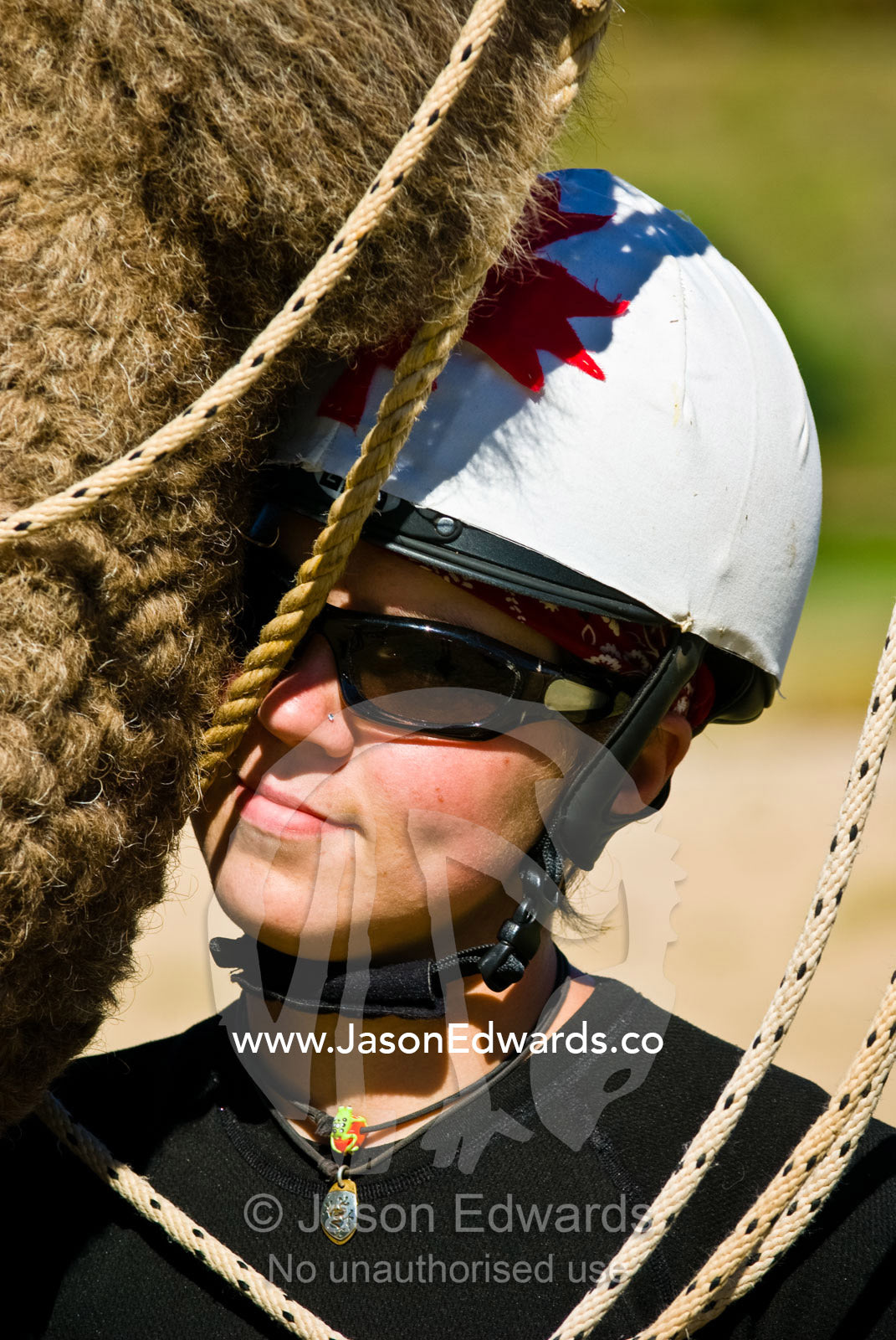 A young jockey nuzzles the thick fur on the neck of her racing camel. Hughenden, Queensland, Australia