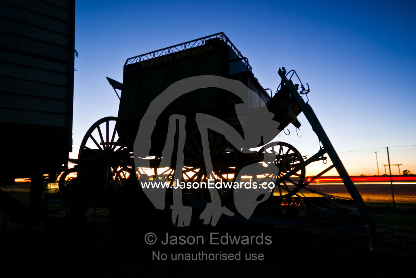 Car headlights pass an antique stage coach in the pre-dawn light. Hughenden, Queensland, Australia