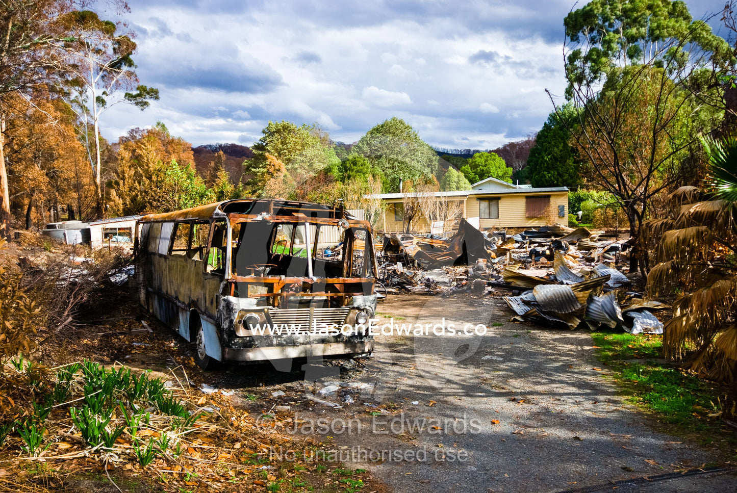 A burnt-out school bus rests beside the charred remains of a house. Hazeldene, Victoria, Australia