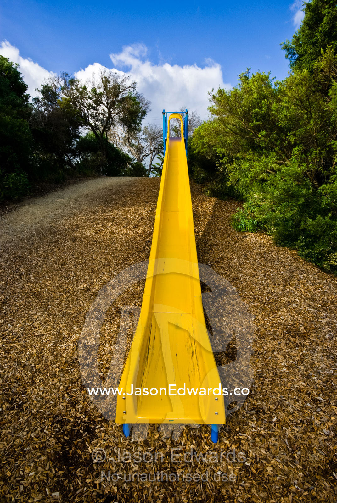 A long, straight bright yellow children's slide in a playground. Sandy Point, Victoria, Australia