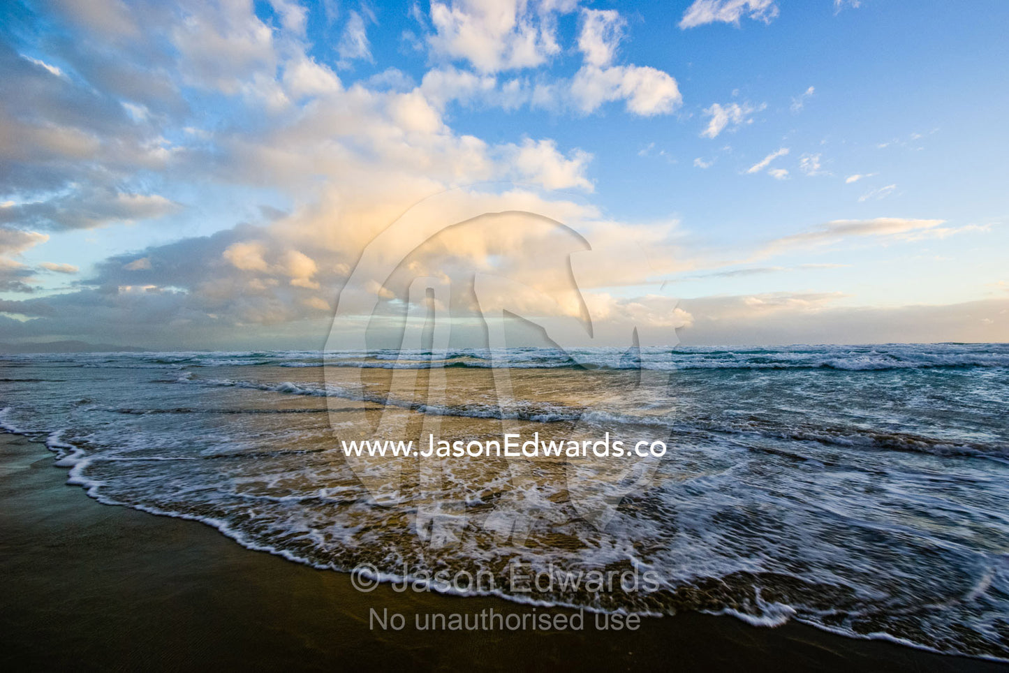 Storm clouds reflect pastel colors in waves rolling into shore. Waratah Bay, Victoria, Australia.