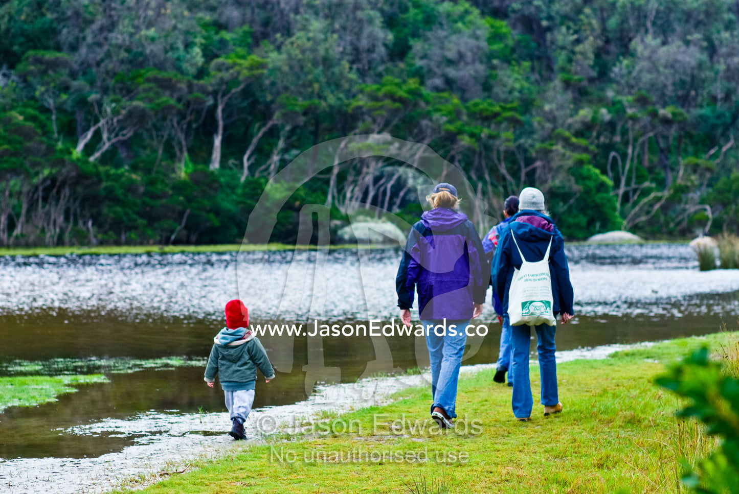 A small boy follows his mother and grandmother on a walk by a river. Tidal River, Wilsons Promontory National Park, Victoria, Australia
