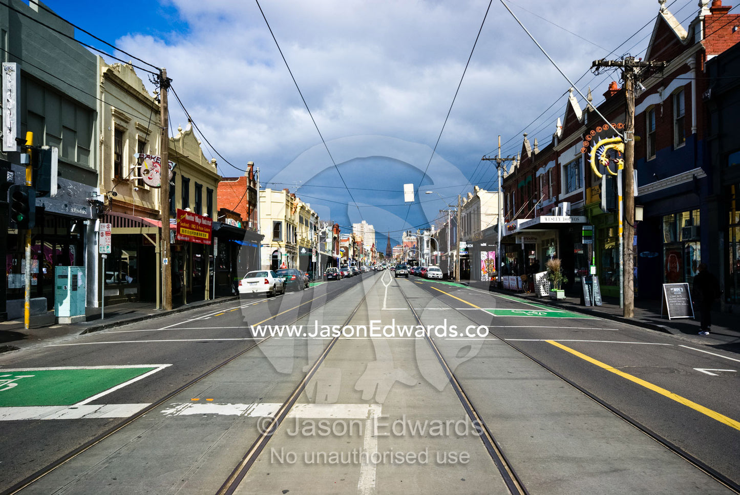 Tram lines running down an inner city road lined with cafes and shops. Brunswick Street, Fitzroy, Victoria, Australia