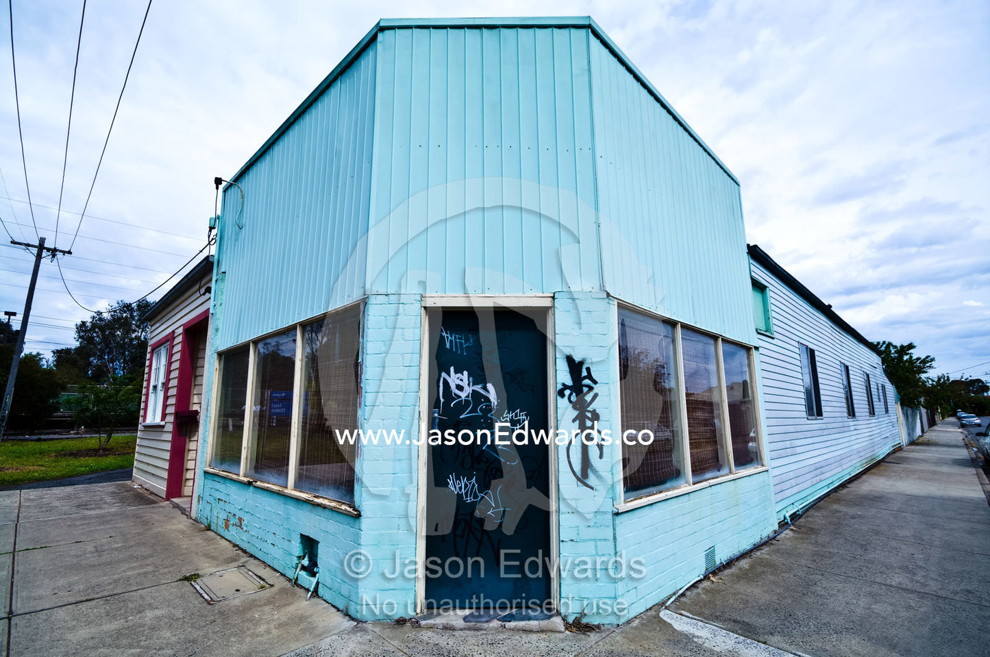 Graffiti on an old corner store painted blue and turned into a house. Fitzroy North, Victoria, Australia